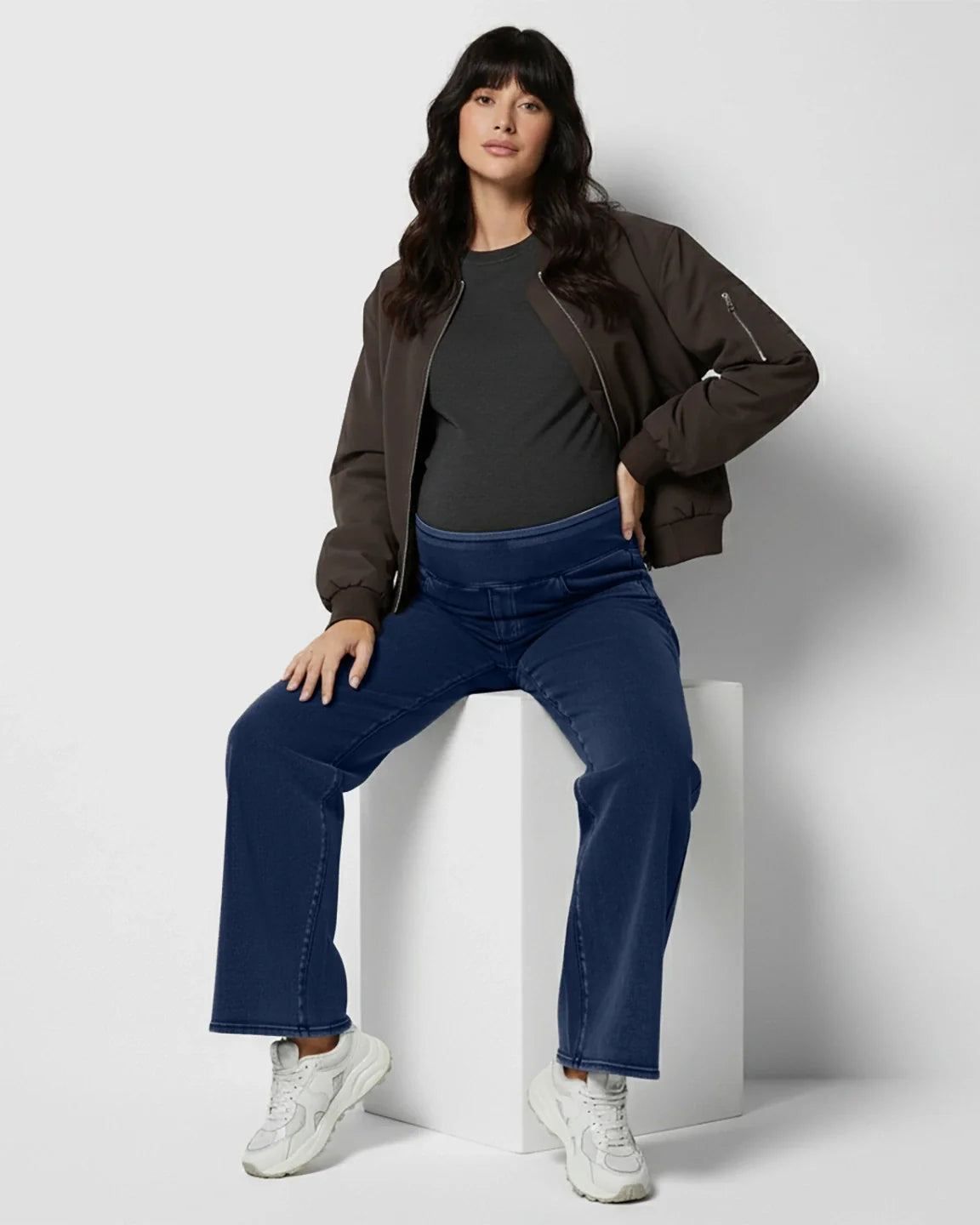 Woman in dark wash wide-leg maternity denim jeans with a soft waistband, black tee, and bomber jacket.