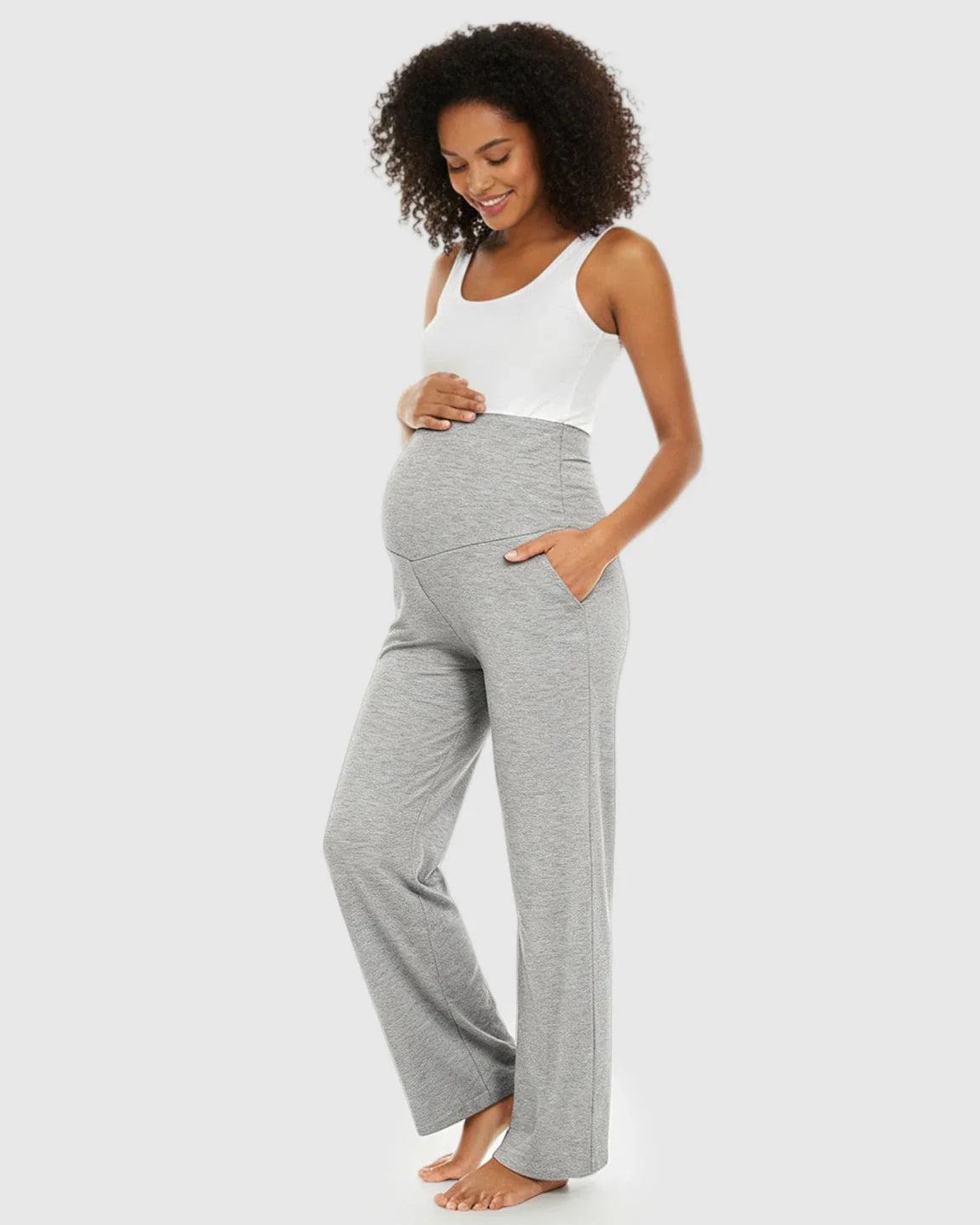 Smiling pregnant woman in gray wide-leg maternity lounge pants with a foldable waistband and side pockets.