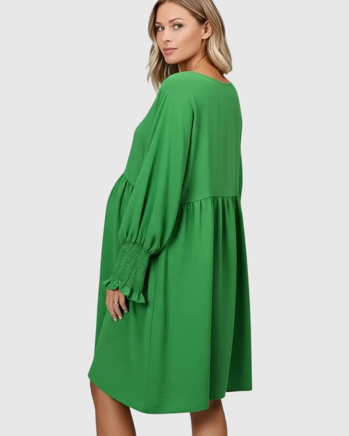 Pregnant woman in a green flowy smocked sleeve casual dress with a round neckline.