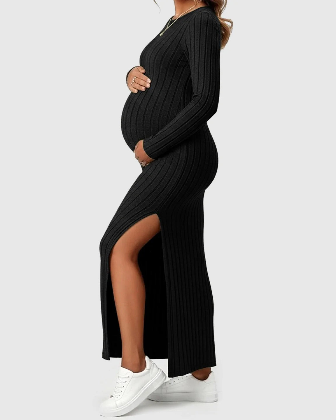 Pregnant woman in a black ribbed knit long-sleeve maternity maxi dress with a high side slit.