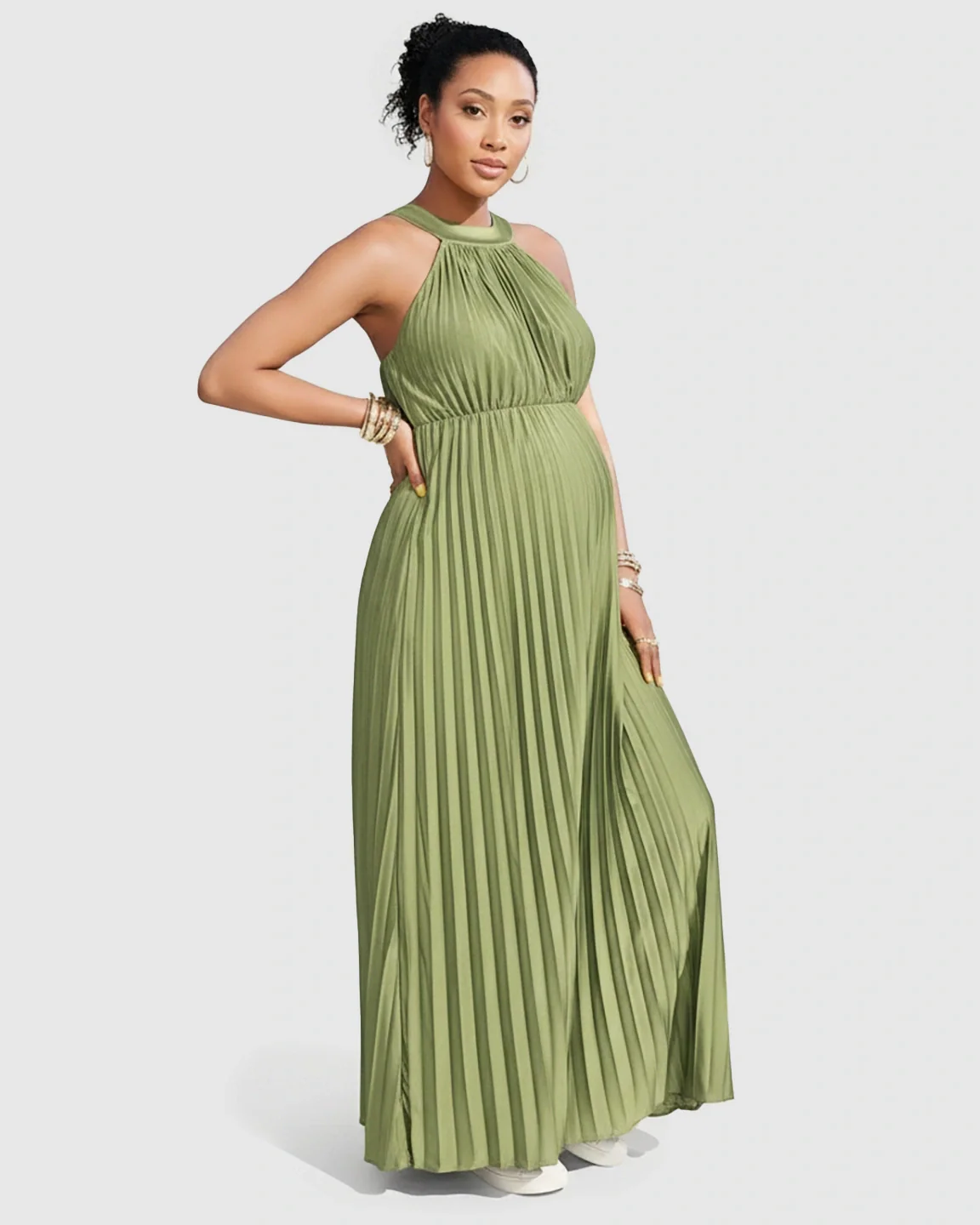 Maternity model in a sage green faux silk halter neck pleated maxi dress, showcasing a flowing silhouette.