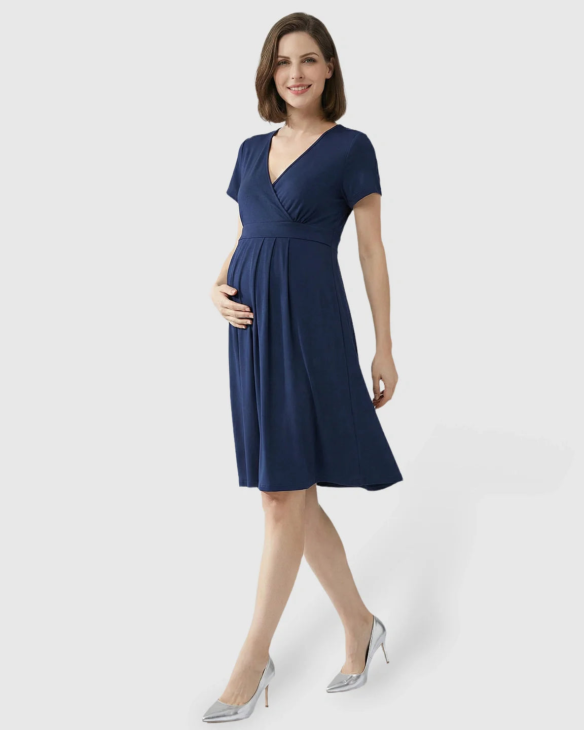 Smiling pregnant woman in a navy V-neck A-line maternity and nursing dress with short sleeves.
