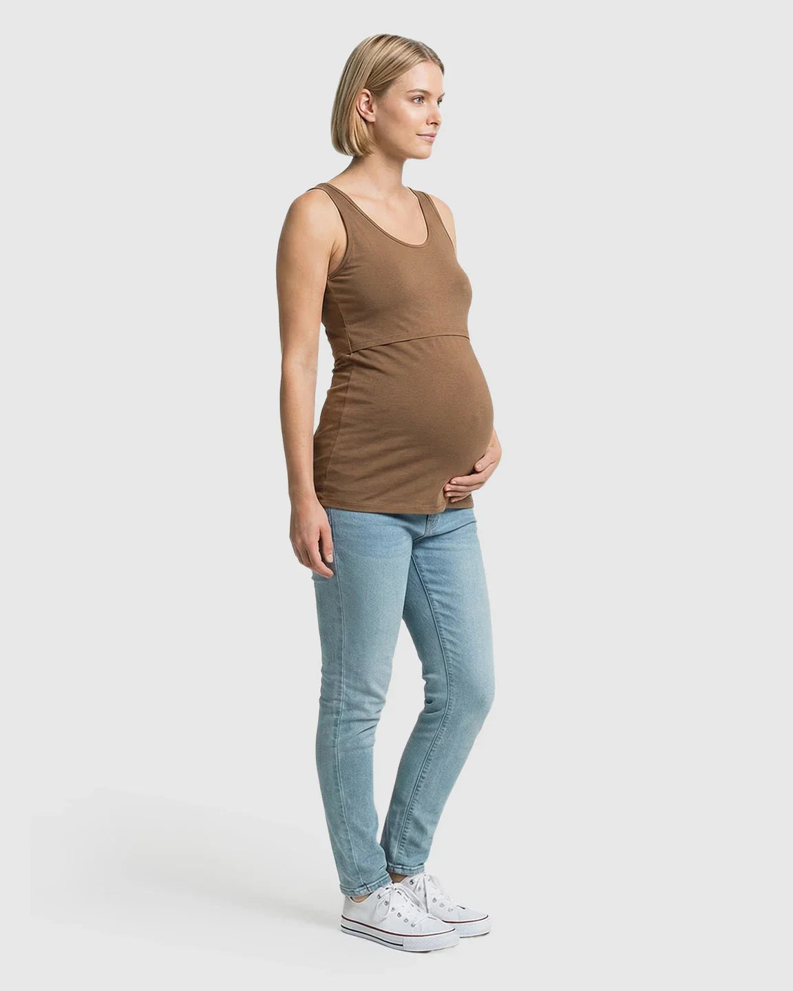 Pregnant woman in a brown stretch nursing-access maternity tank top and light blue jeans.
