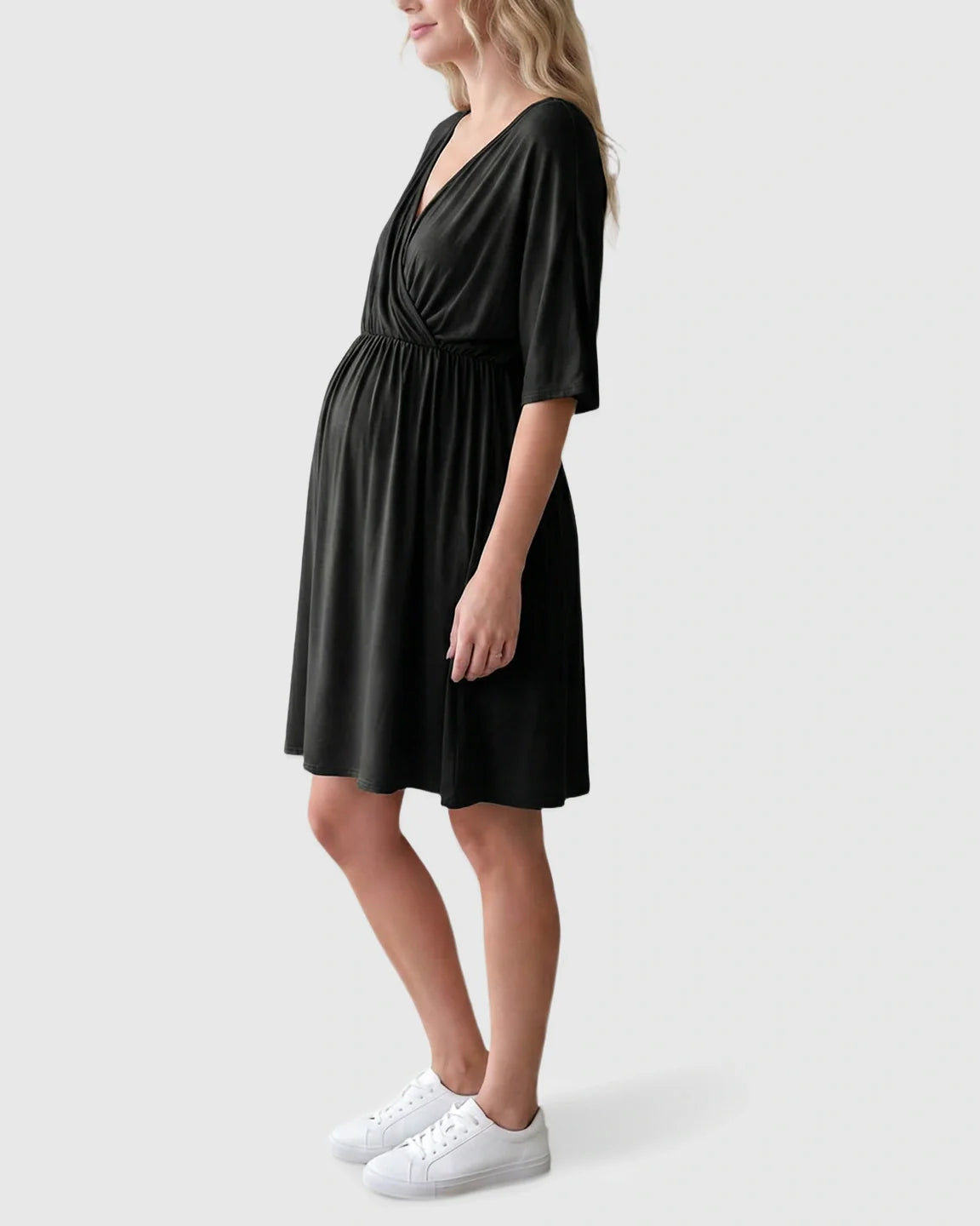 Black cross-front maternity midi dress with 3/4 sleeves and A-line silhouette, worn by a pregnant woman.