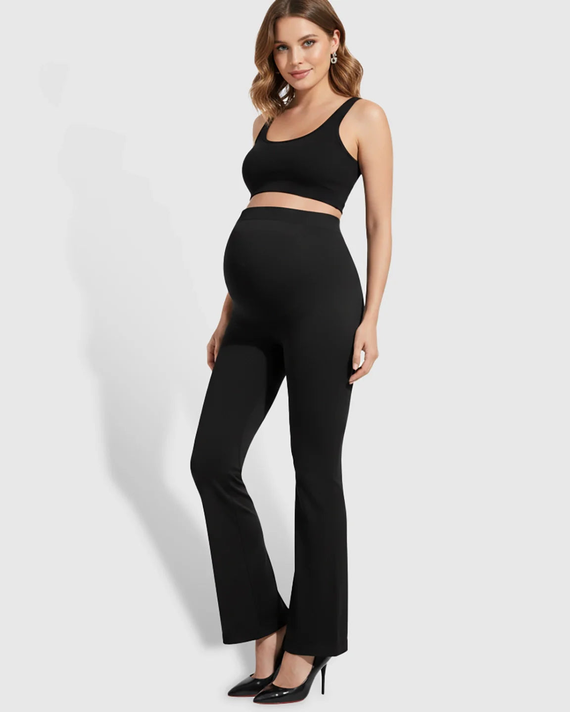 Pregnant woman in black over-belly bootcut maternity pants and matching crop top.