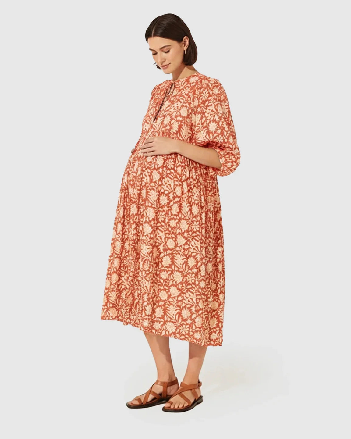 Pregnant woman in a loose-fit terracotta floral maternity midi dress with gathered shoulders and puff sleeves.
