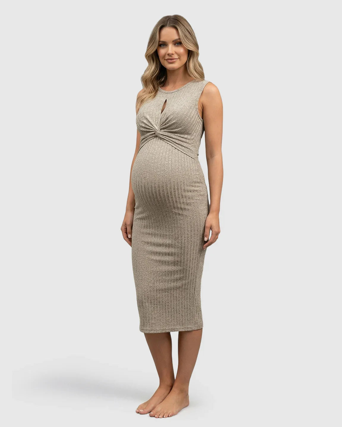 Blonde pregnant woman in a ribbed beige bodycon maternity midi dress with a twisted knot chest.