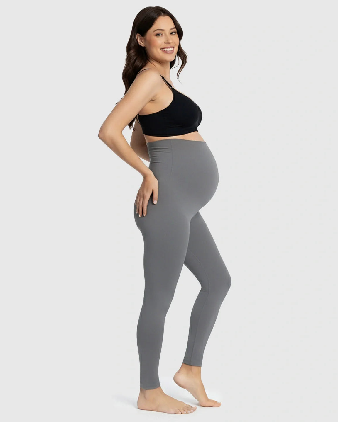 Smiling pregnant woman in charcoal gray Bump Society Belly Support Stretch Maternity Leggings and black bra.