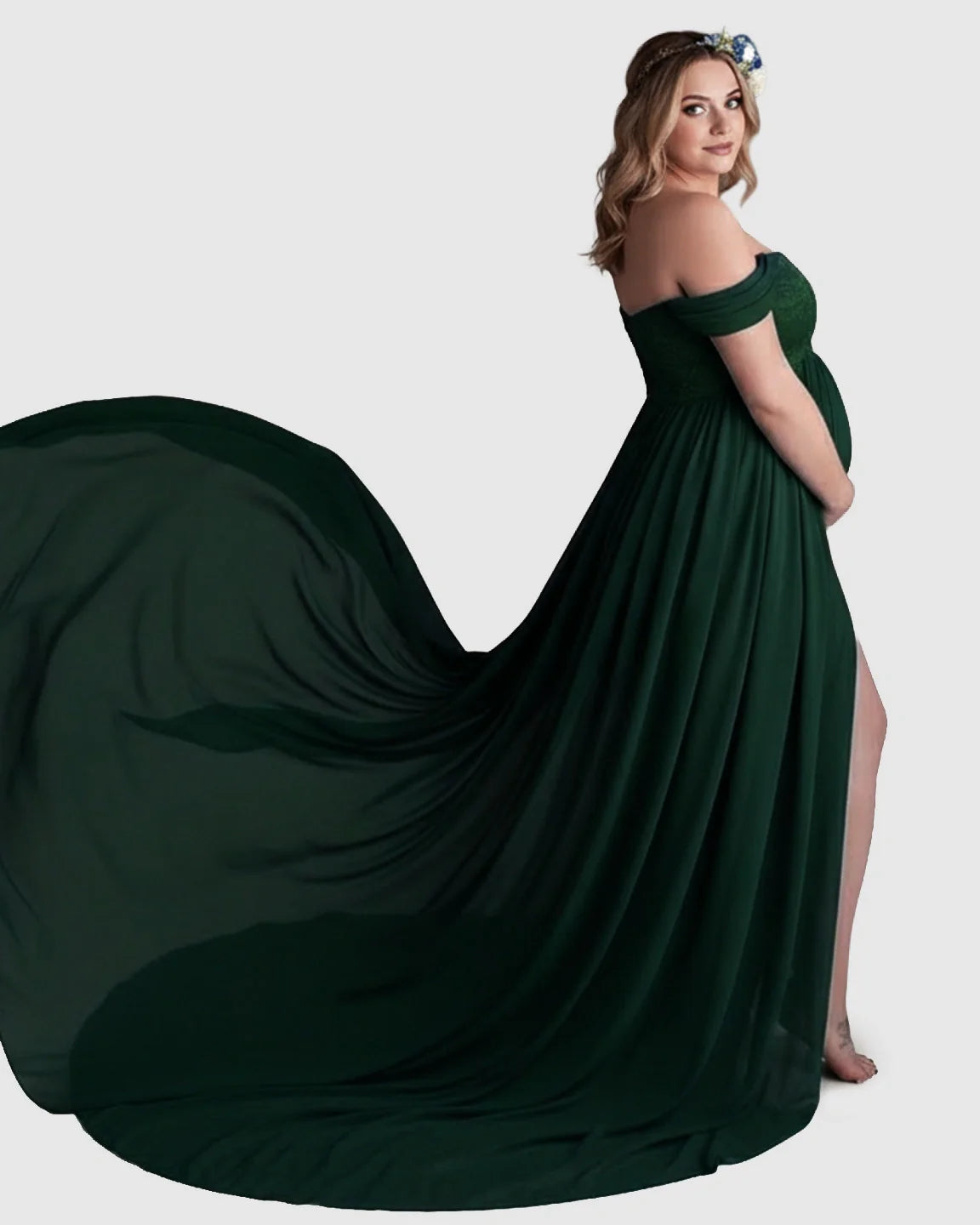Pregnant woman in an emerald green off-shoulder chiffon maternity gown with an extra-long flowing train.