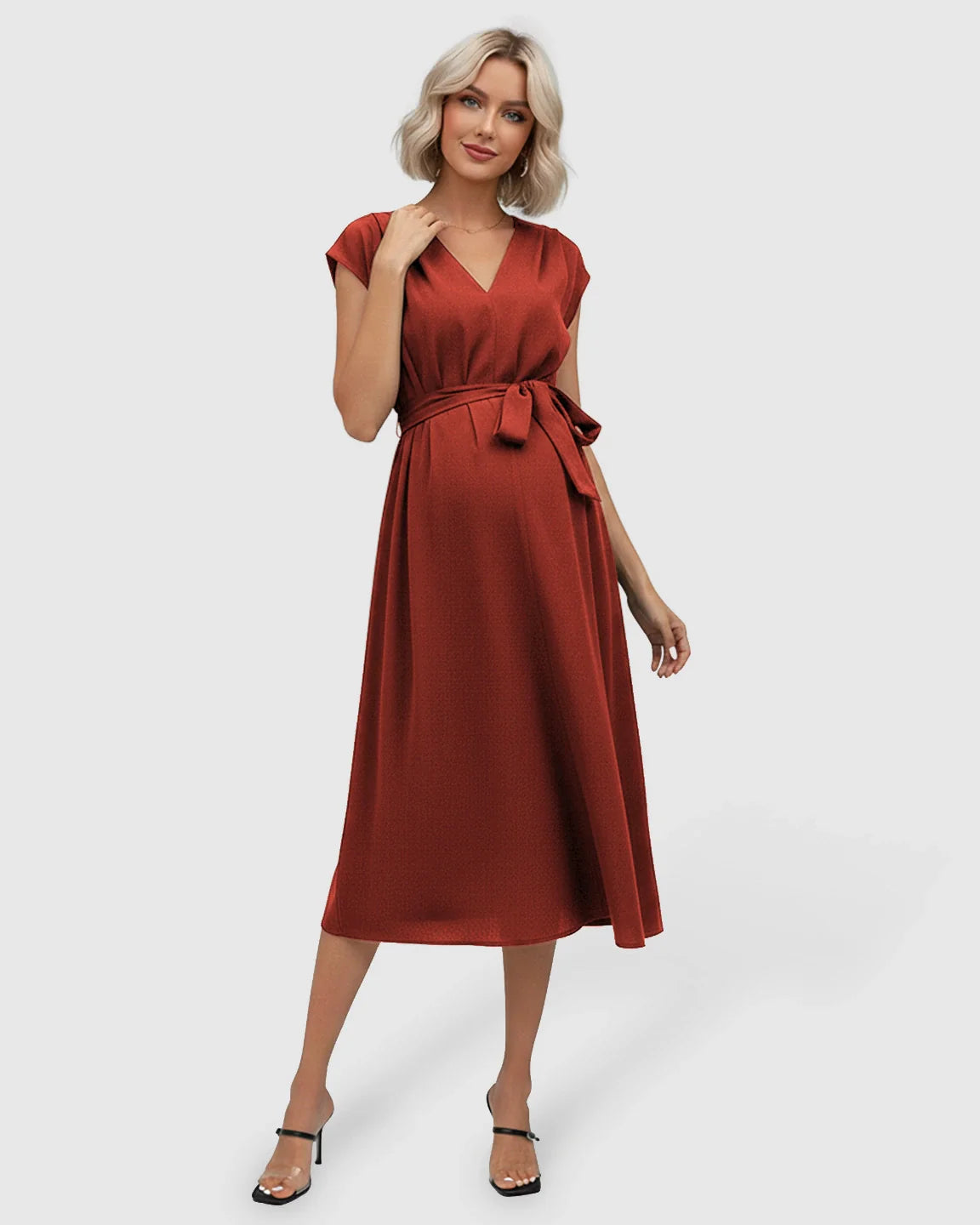 Smiling pregnant woman in a rust-colored V-neck tie-waist maternity midi dress with flutter sleeves.