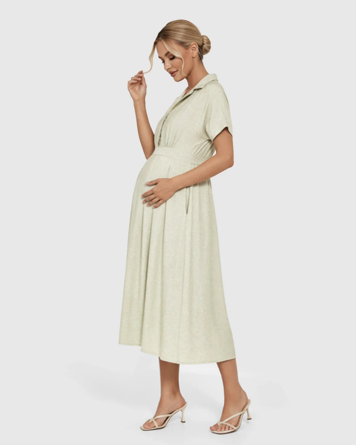 Pregnant woman in a light green Lapel Collar A-line Maternity Midi Dress with short sleeves, holding her bump.