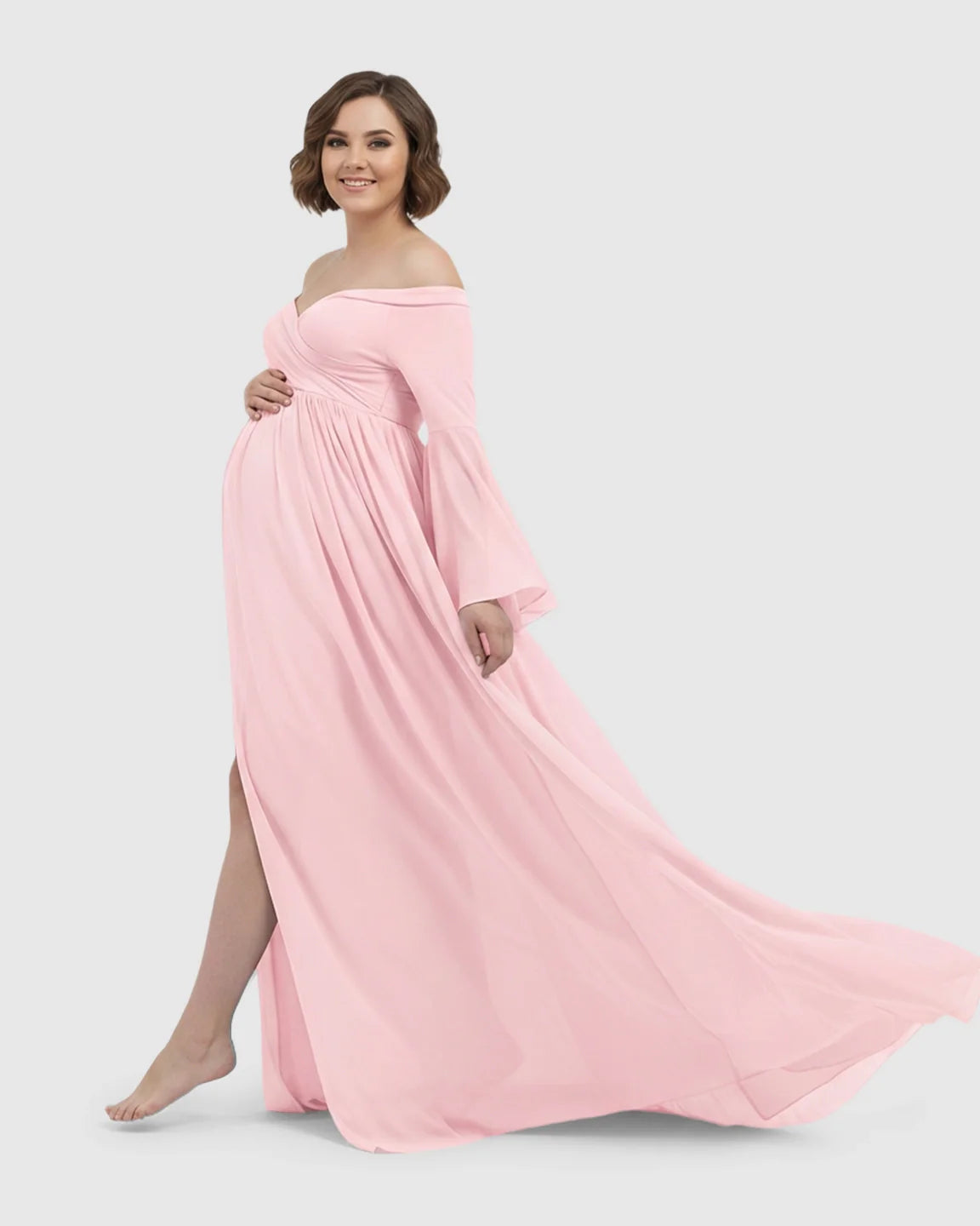 Smiling pregnant woman in a pink off-shoulder chiffon maternity gown with bell sleeves and a long train.