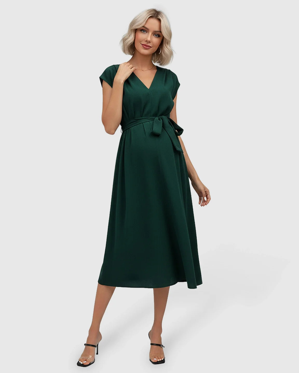 Blonde model in a dark green V-neck maternity midi dress with flutter sleeves and an adjustable tie-waist.