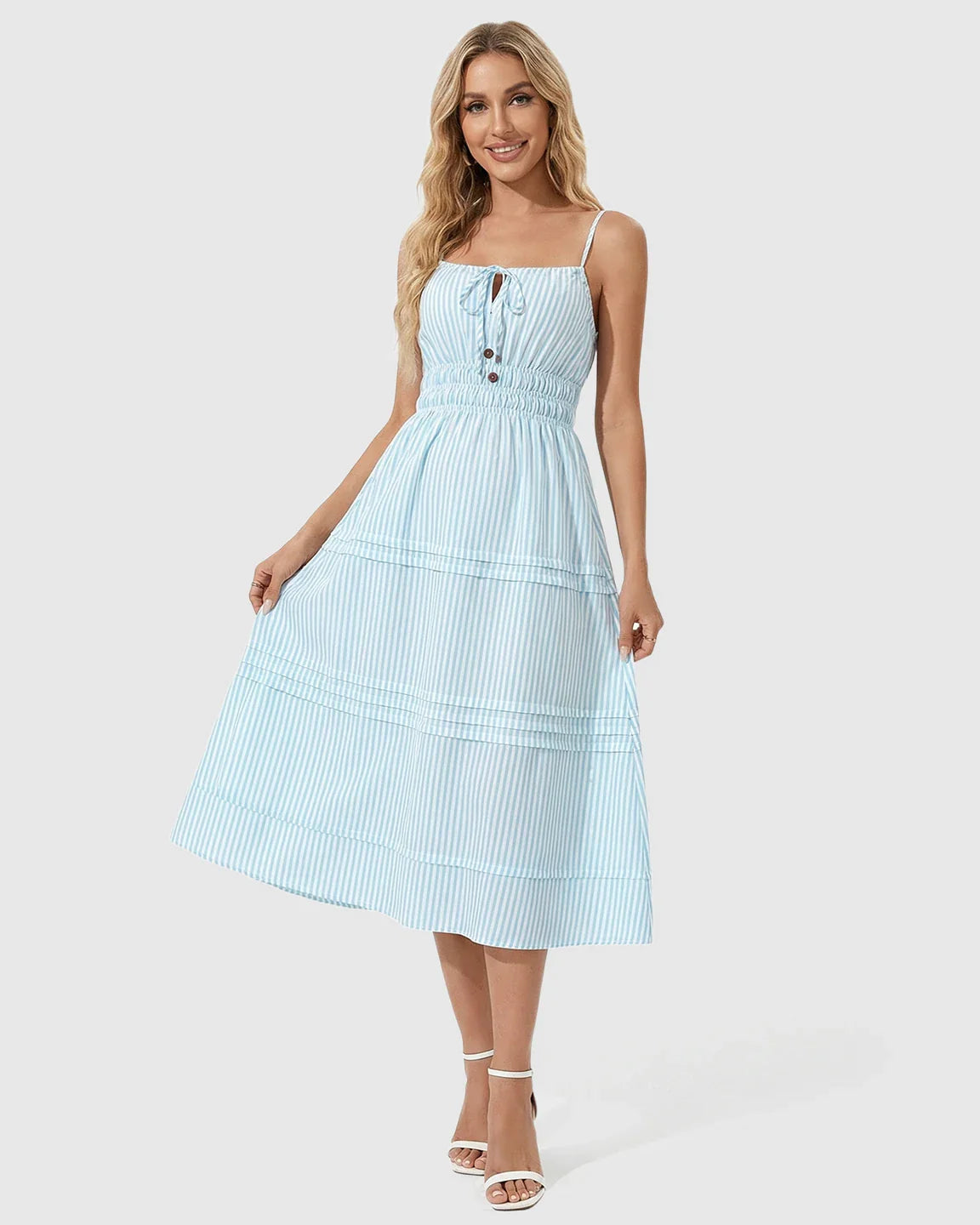 Smiling woman in a blue and white striped smocked-waist maternity midi dress with spaghetti straps.