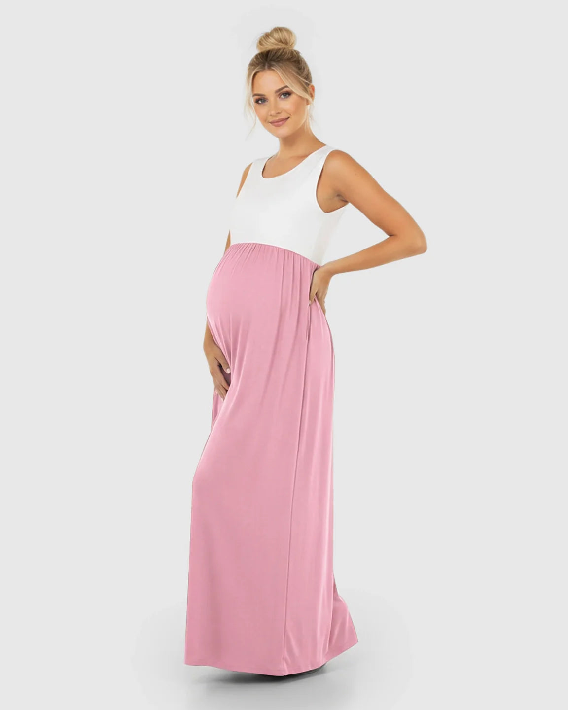 Smiling pregnant woman in a white and pink colorblock high-waisted maternity maxi dress.