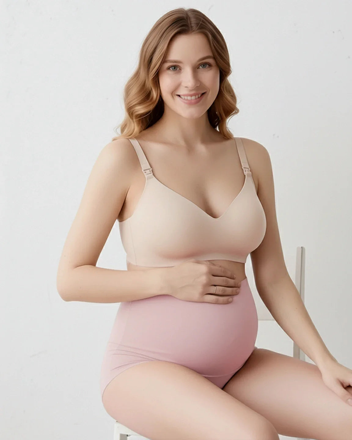 Smiling pregnant woman wearing a nude seamless maternity bra and pink full-coverage high-waist briefs.