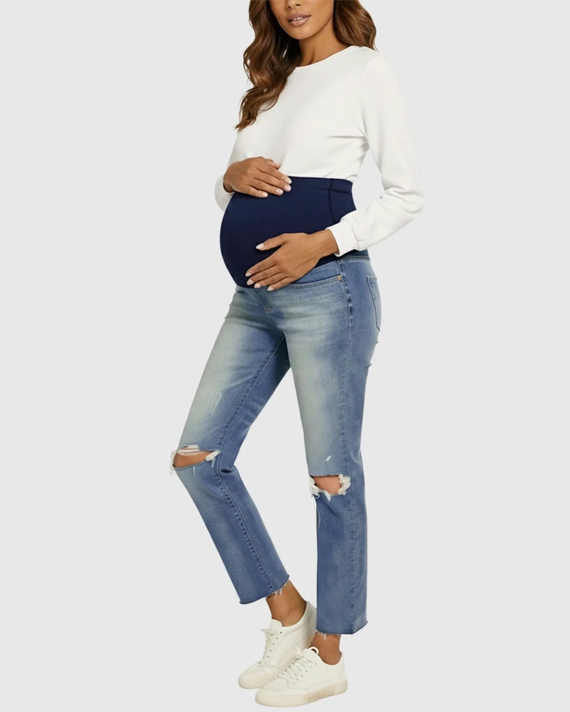Pregnant woman in distressed light wash maternity jeans with a navy high waist belly band.