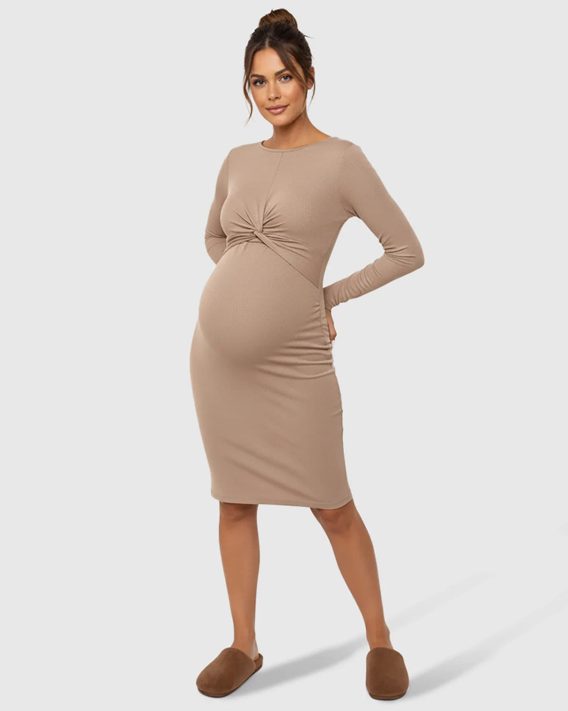 Maternity model in a beige ribbed bodycon dress with a twist-front detail and empire waist.