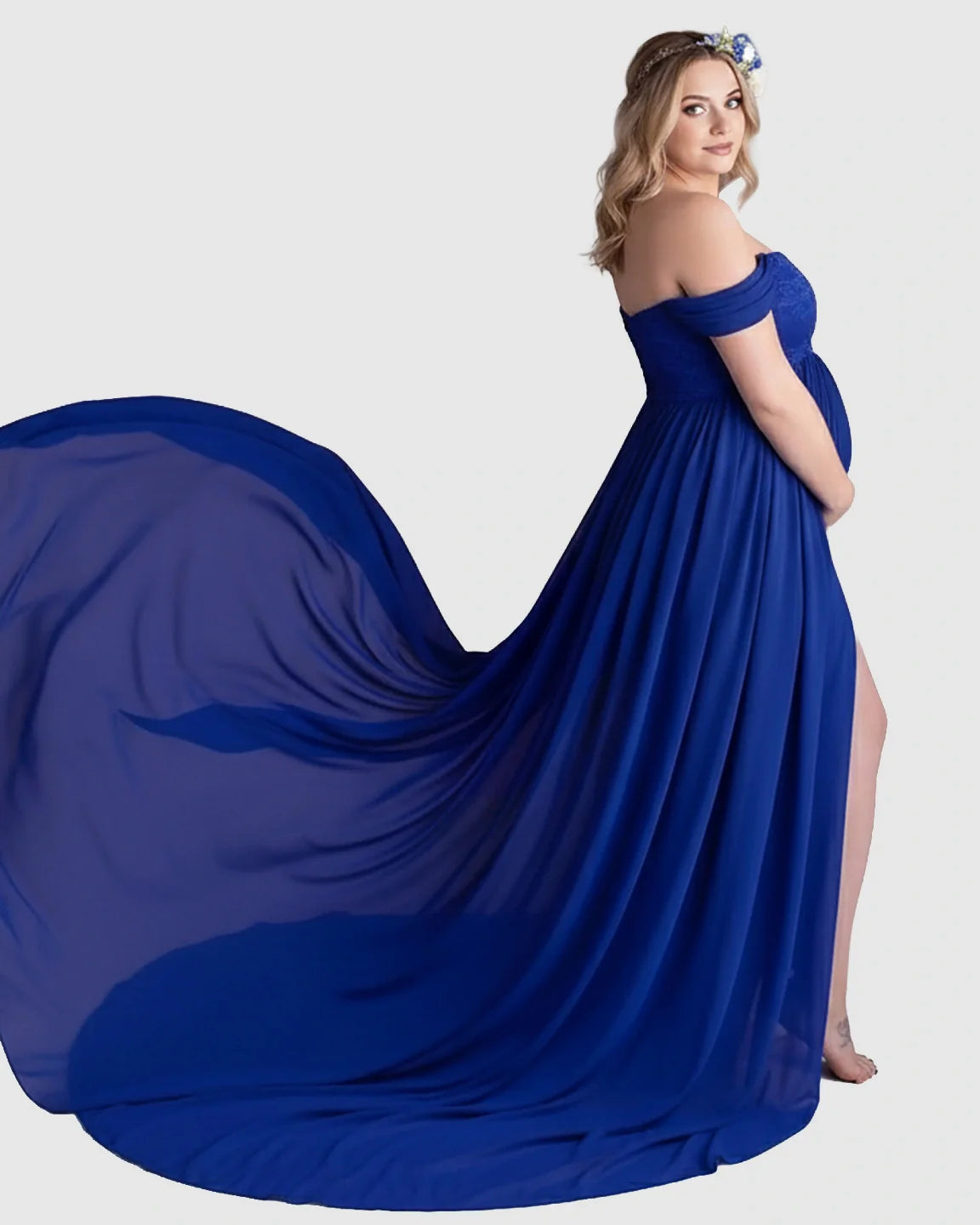 Blonde pregnant woman in a royal blue off-shoulder chiffon maternity gown with an extra-long flowing train.