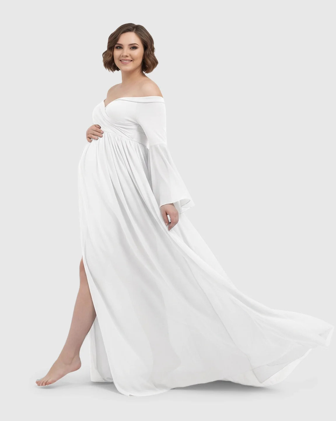 White off-shoulder maternity gown with bell sleeves, long train, and high slit, worn by a smiling pregnant woman.