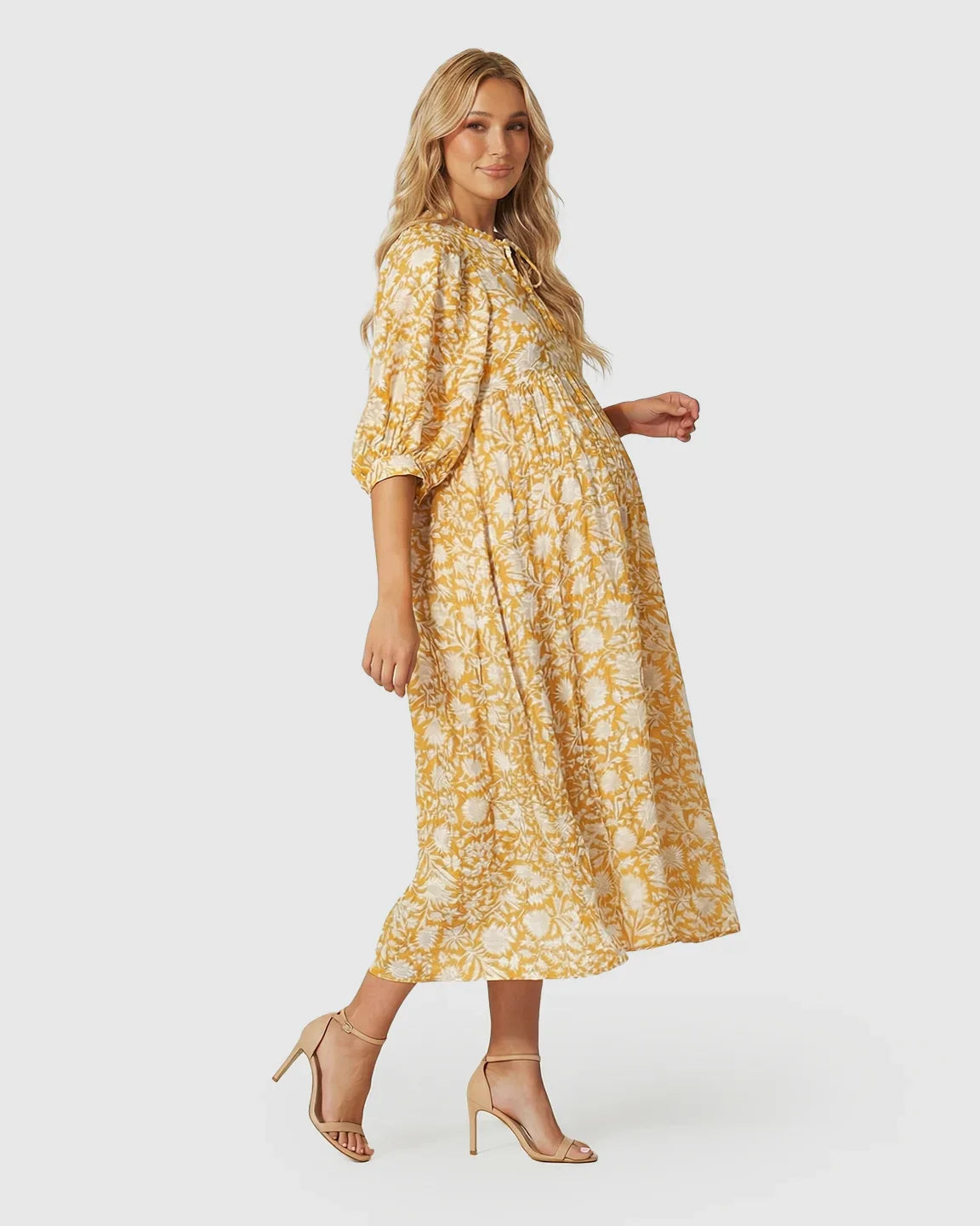Pregnant woman in a yellow and white floral loose-fit maternity midi dress with gathered shoulders and puff sleeves.