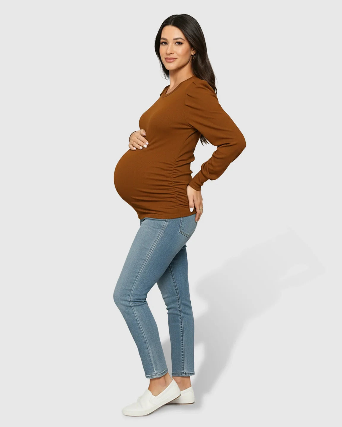 Pregnant woman wearing a warm brown long-sleeve ruched maternity top with a round neck and side pleats.