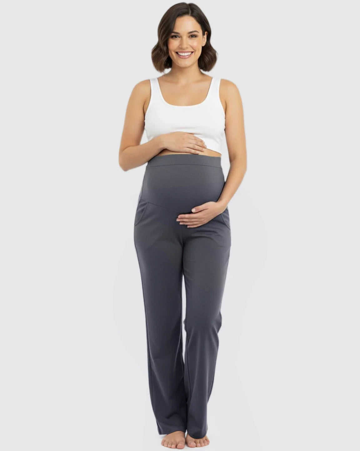 Smiling pregnant woman in charcoal gray stretch flared maternity pants with an over-belly waistband and pockets.