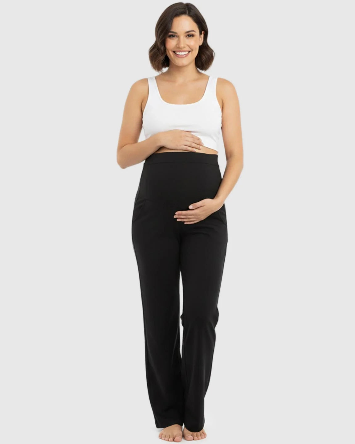 Smiling pregnant woman in black stretch flared maternity pants with over-belly waistband and pockets.