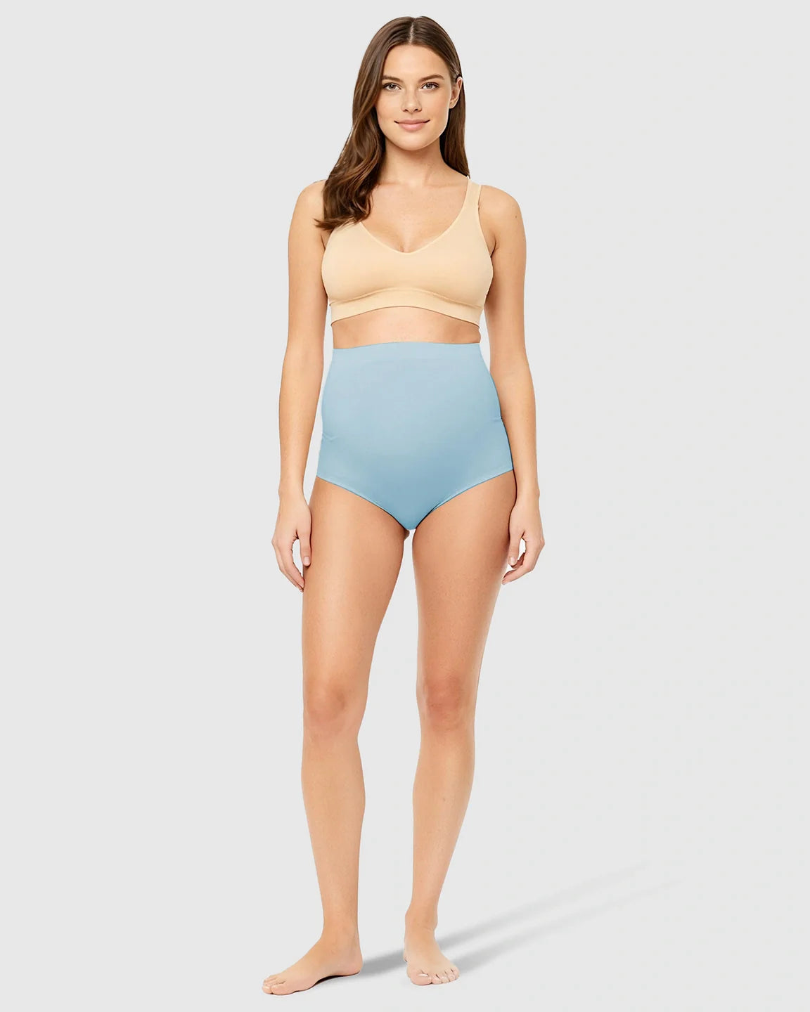 Woman in light blue high-waist seamless belly-support maternity underwear and a nude bra.