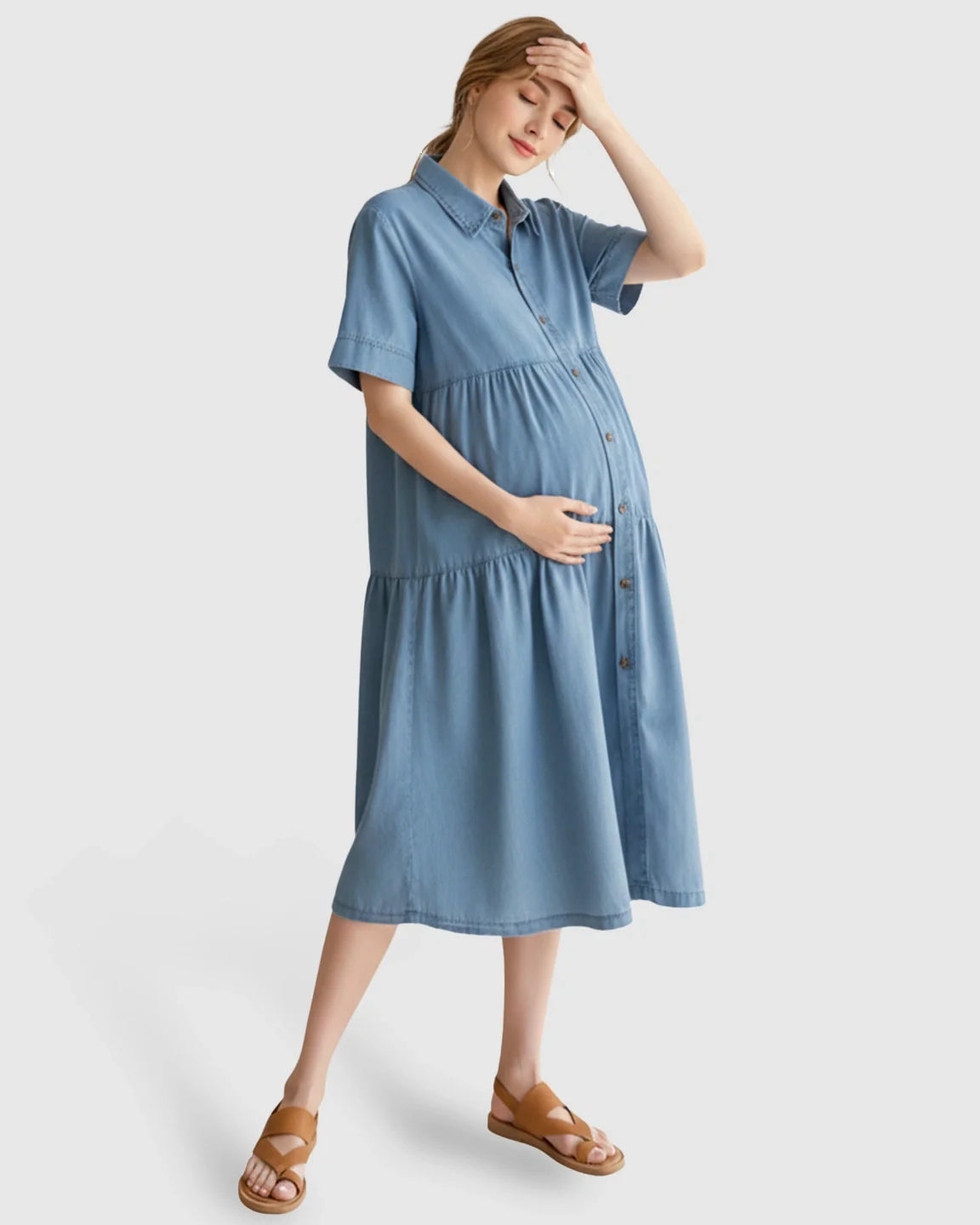 Maternity midi dress in light blue tiered denim with button-front, short sleeves, and relaxed fit.