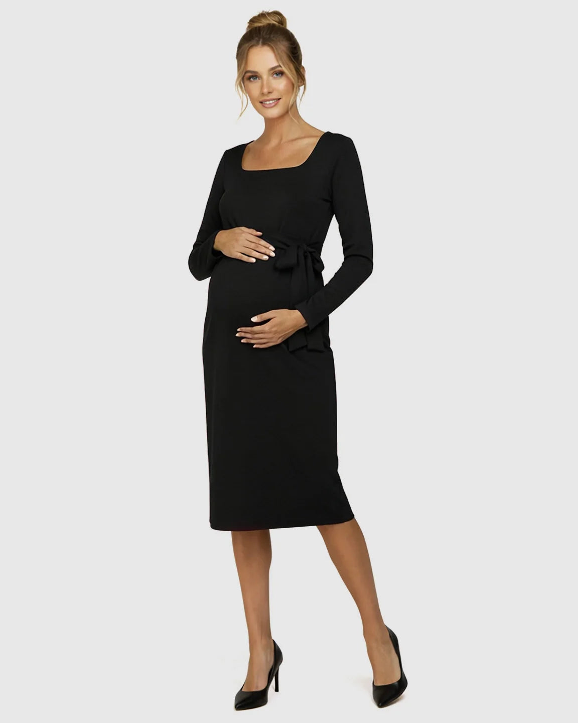 Pregnant woman in a black square neck, long-sleeve bodycon maternity midi dress with side-tie detail.