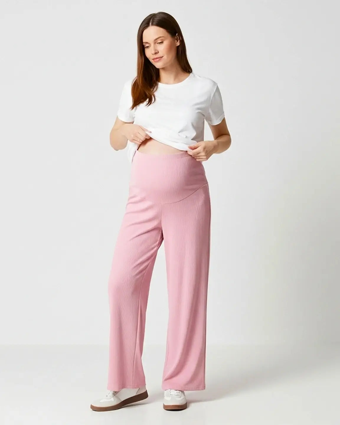 Woman in pink ribbed wide-leg maternity pants with over-bump waistband and white t-shirt.