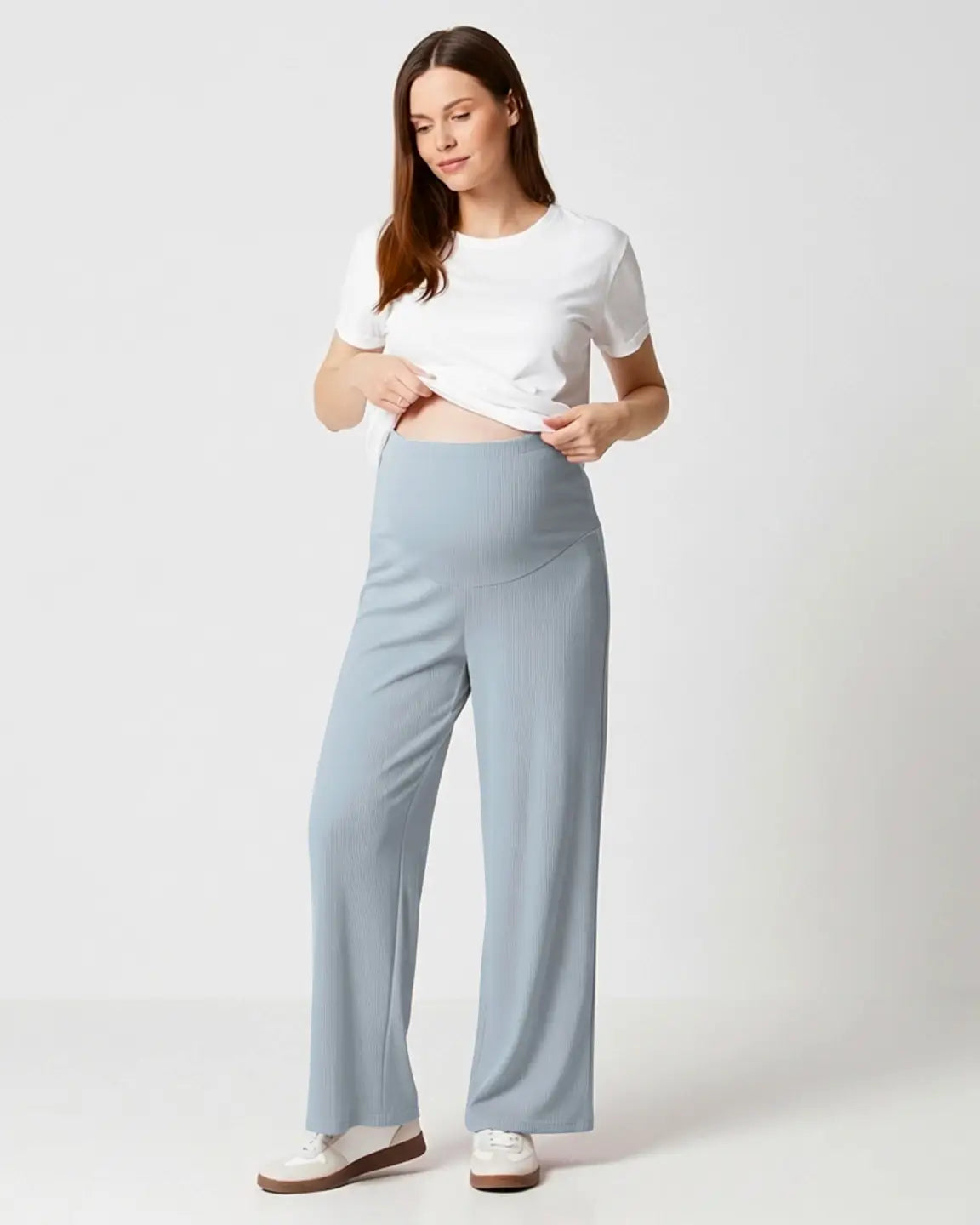 Woman in soft blue ribbed wide-leg maternity pants with over-bump waistband and white tee.
