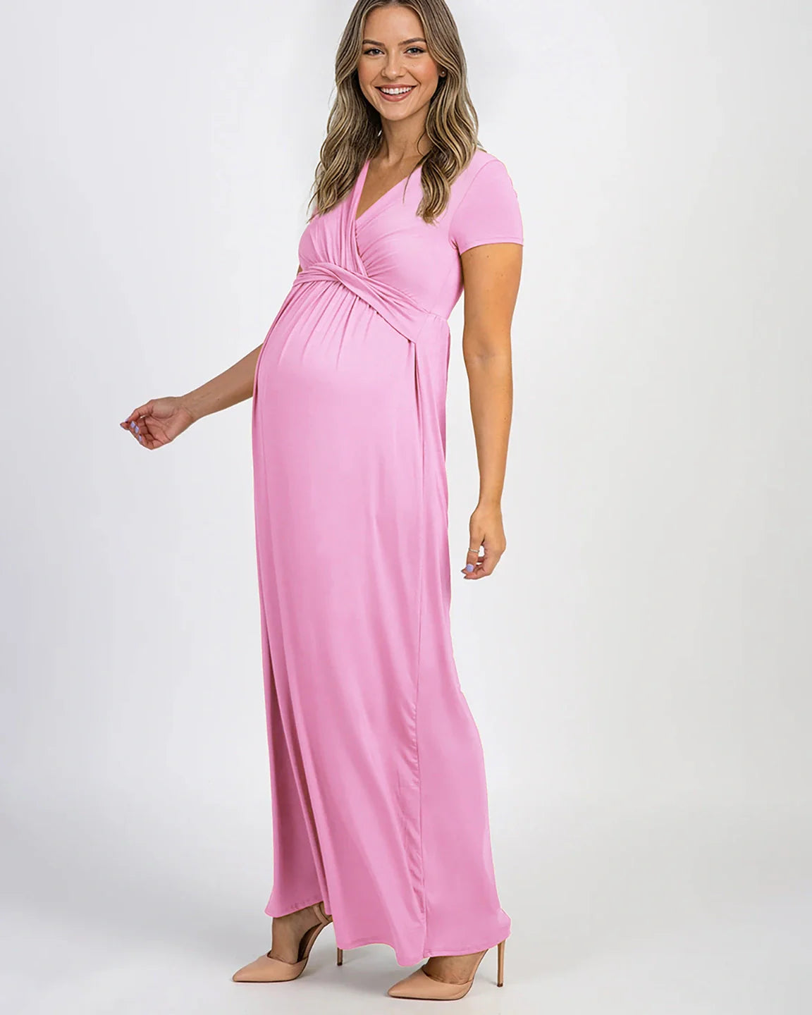 Smiling pregnant woman in a pink twist-front draped maternity nursing maxi dress with short sleeves.