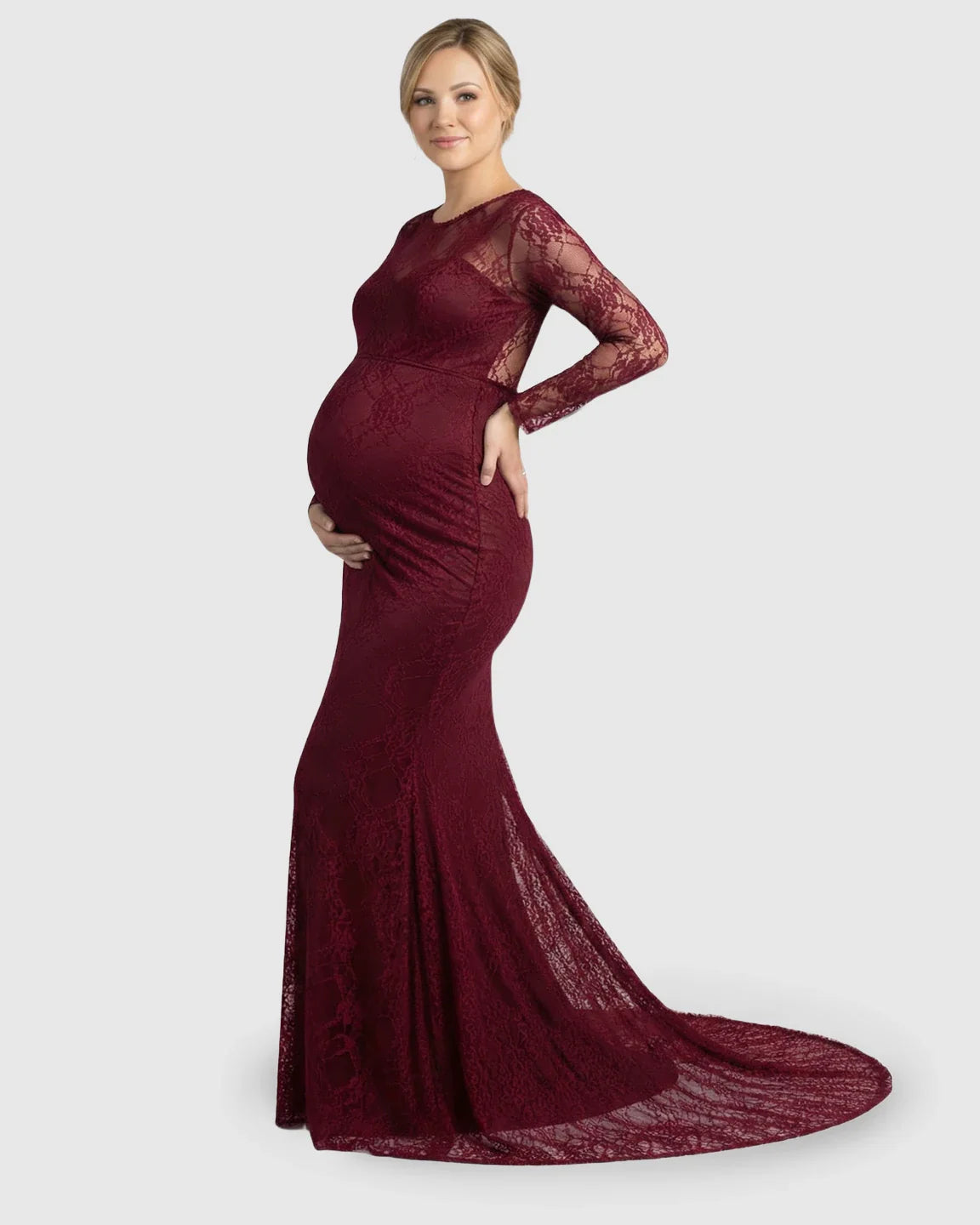 Pregnant woman in a long-sleeved, sheer burgundy lace trumpet maternity gown with a mermaid-style skirt.
