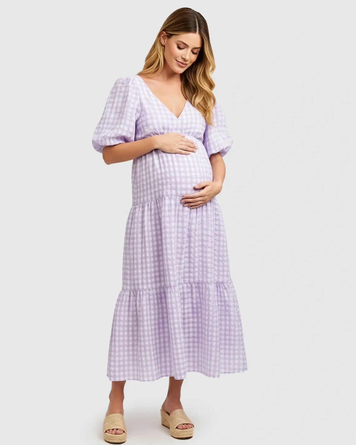 Pregnant woman in a lavender gingham puffed sleeve V-neck tiered maxi dress.