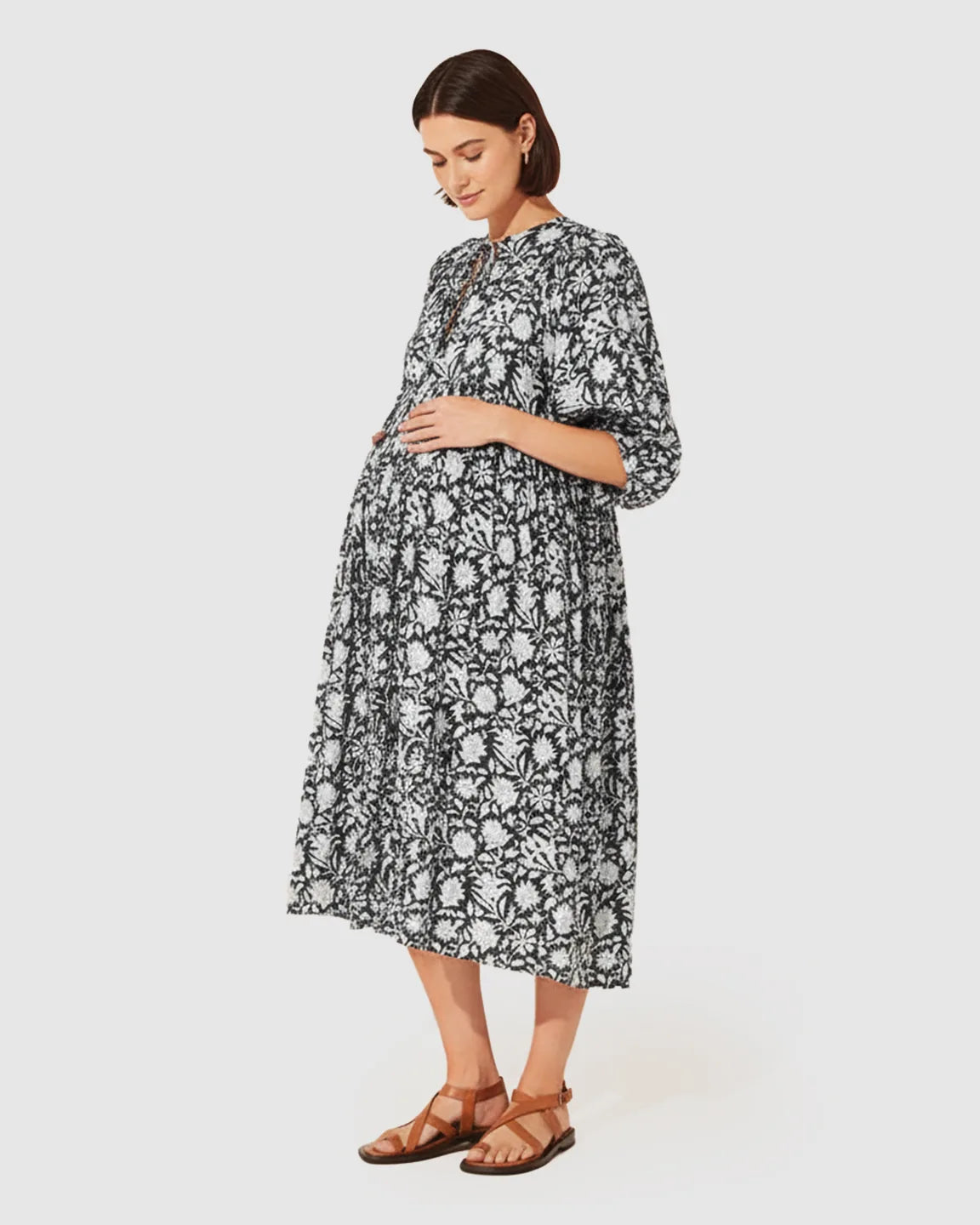 Pregnant woman in a black and white floral loose-fit maternity midi dress with gathered shoulders and puff sleeves.