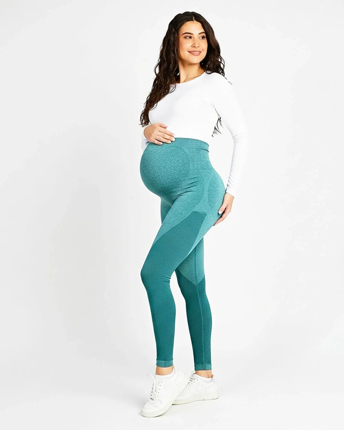 Pregnant woman in teal high-waisted, body-hugging maternity leggings with subtle textured details.