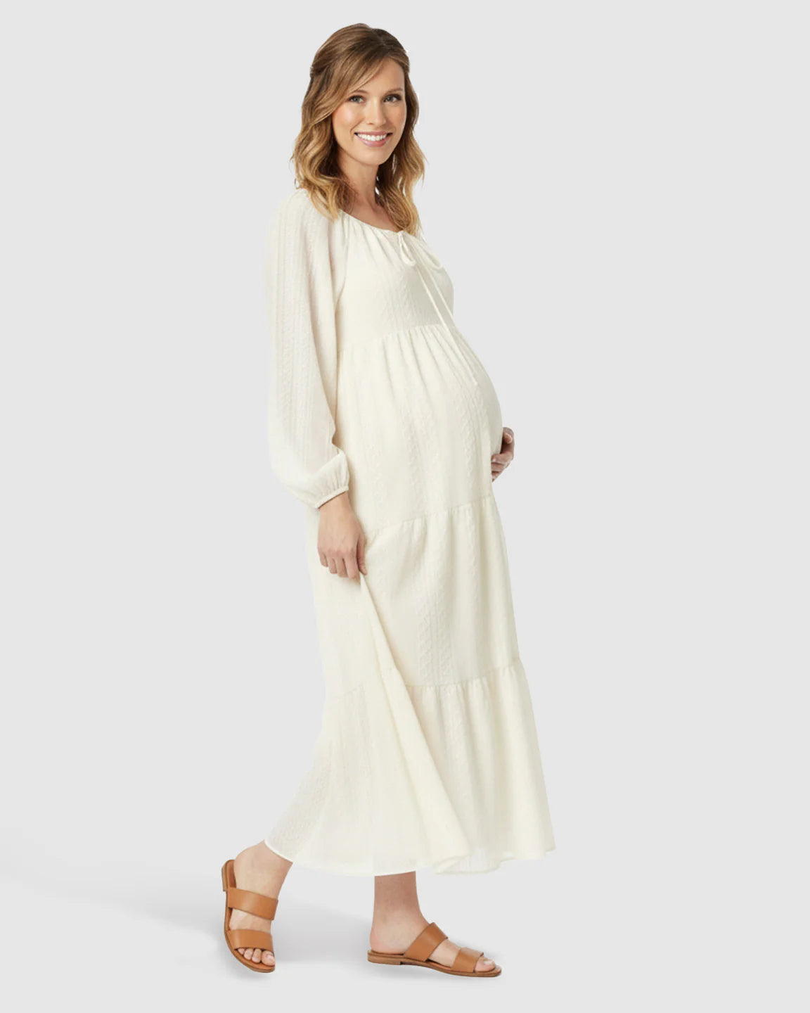 Maternity midi dress in cream with long voluminous sleeves, tie-front neckline, and tiered skirt.