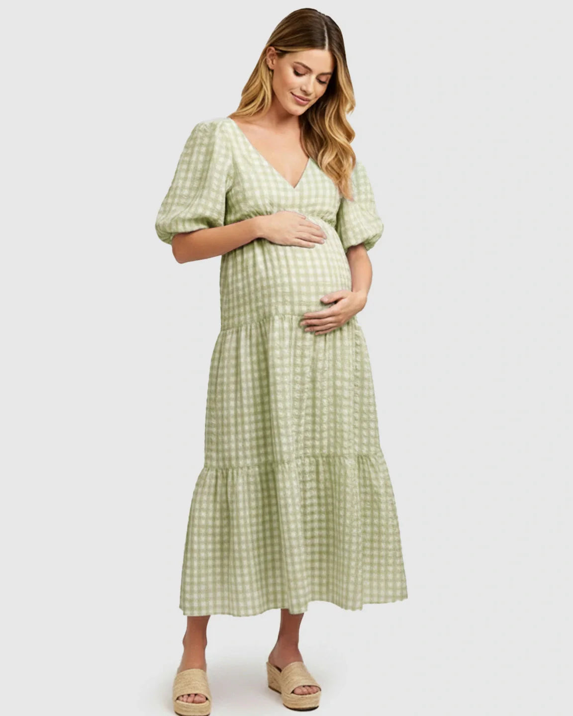 Pregnant woman in a green and white checkered maternity maxi dress with puffed sleeves and a V-neck.