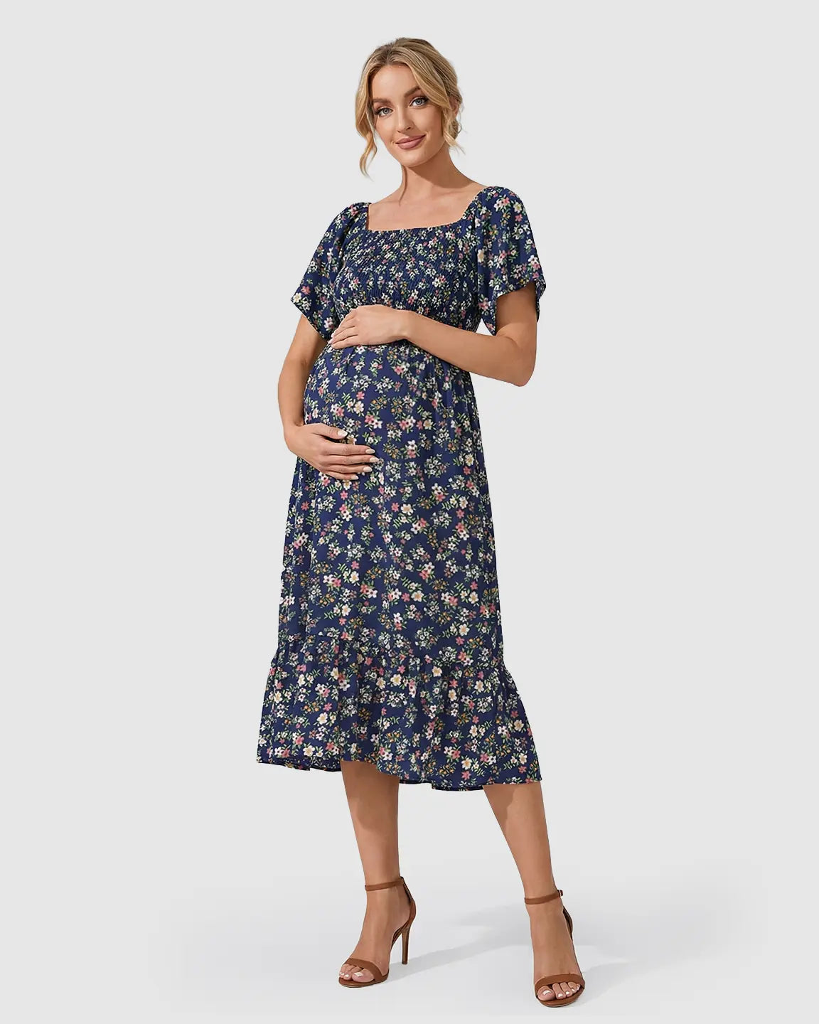 Smiling pregnant woman in a navy floral flutter-sleeve smocked maternity midi dress.