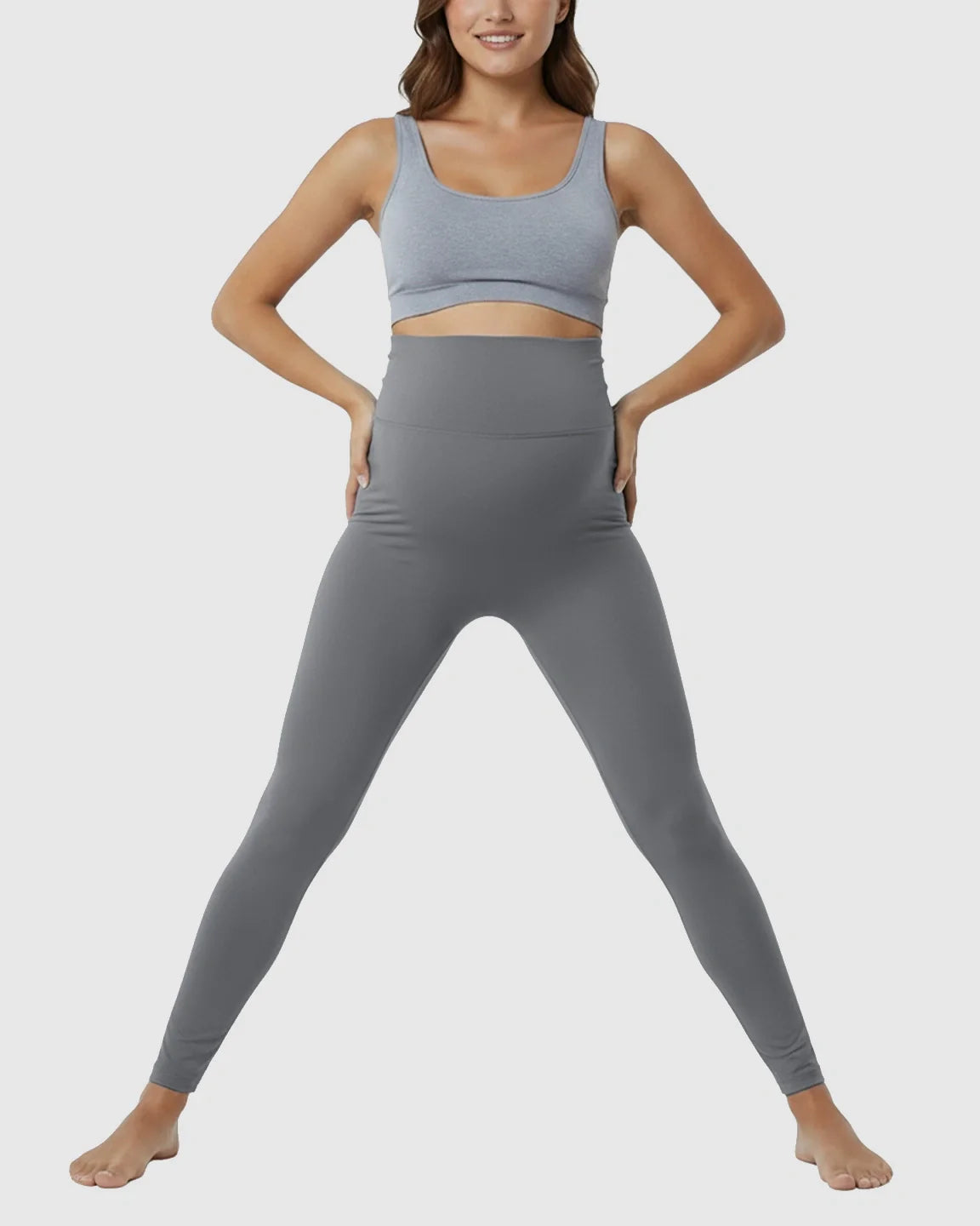 Smiling woman in gray high-waist maternity support leggings and matching sports bra.