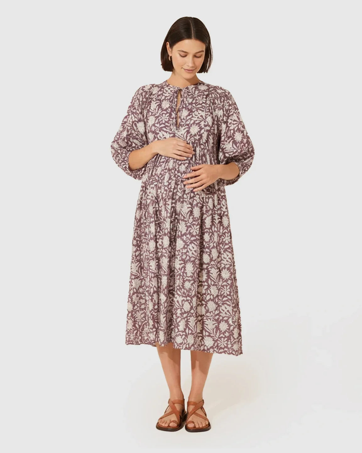 Maternity midi dress in purple and white floral print with gathered shoulders, puff sleeves, and knot detail.