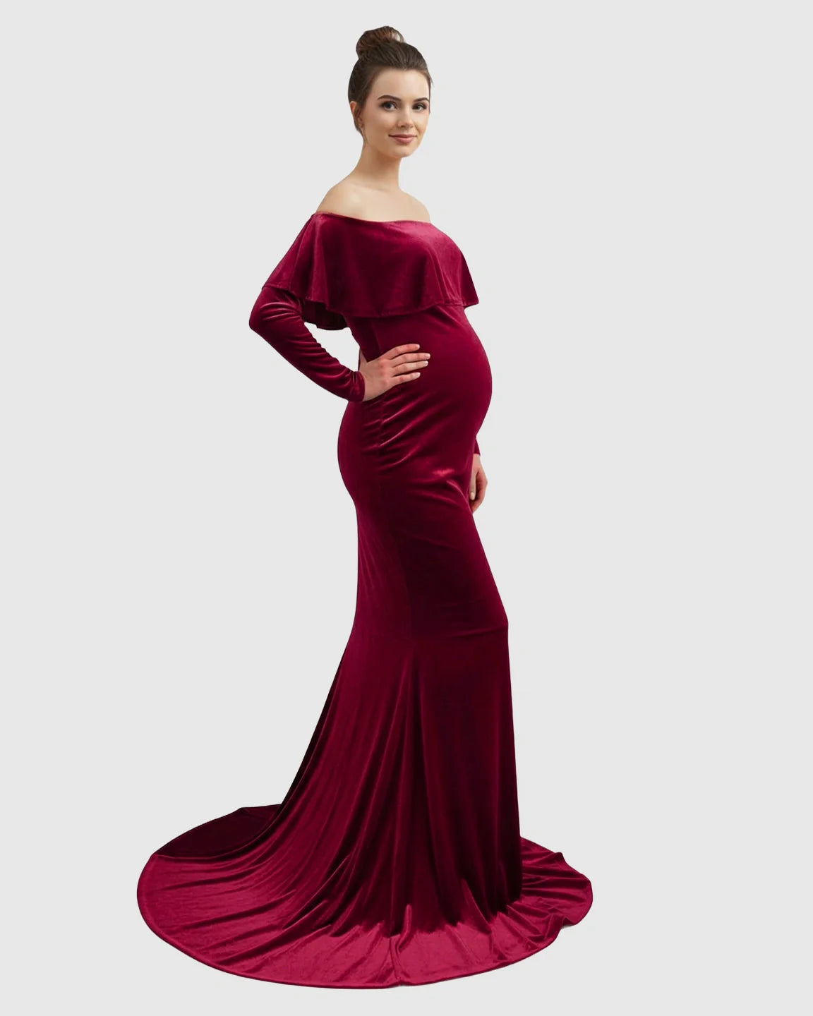 Elegant red velvet off-shoulder maternity gown with a flowing train, highlighting a pregnant woman's bump.