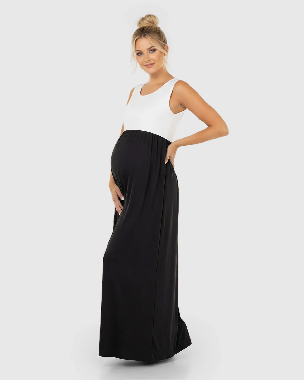 Smiling pregnant woman in a white and black colorblock high-waisted maternity maxi dress with a round neck.