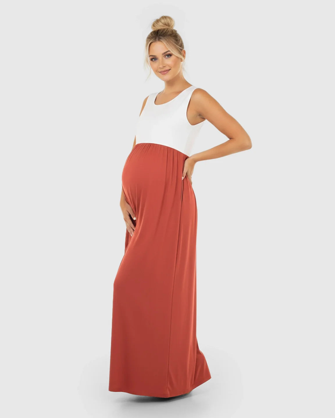 Smiling pregnant woman in a white and rust colorblock high-waisted maternity maxi dress.