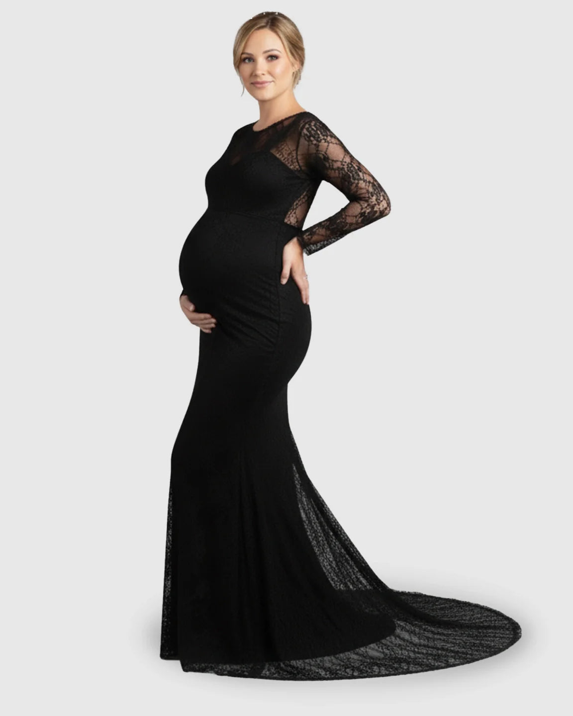 Pregnant woman in a black sheer lace trumpet maternity gown with long sleeves and a mermaid-style skirt.
