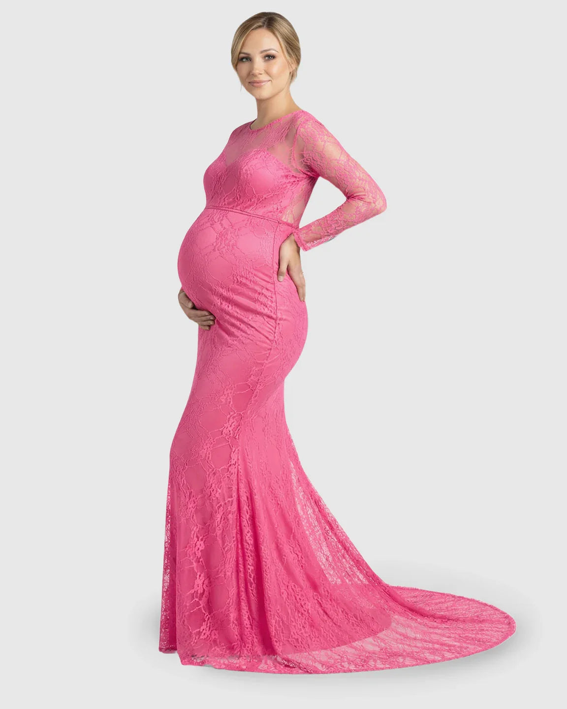 Pregnant woman in a pink sheer lace trumpet maternity gown with long sleeves and a mermaid-style skirt.