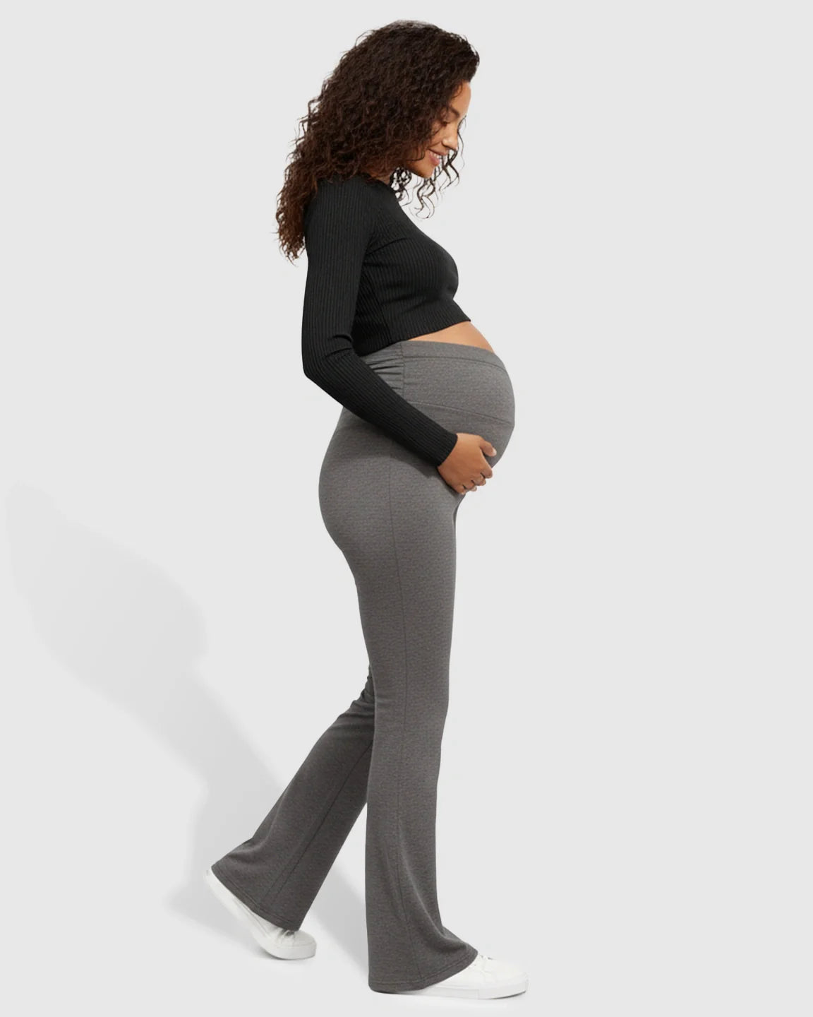 Pregnant woman in gray Bump Society crossed waistband flared maternity pants.