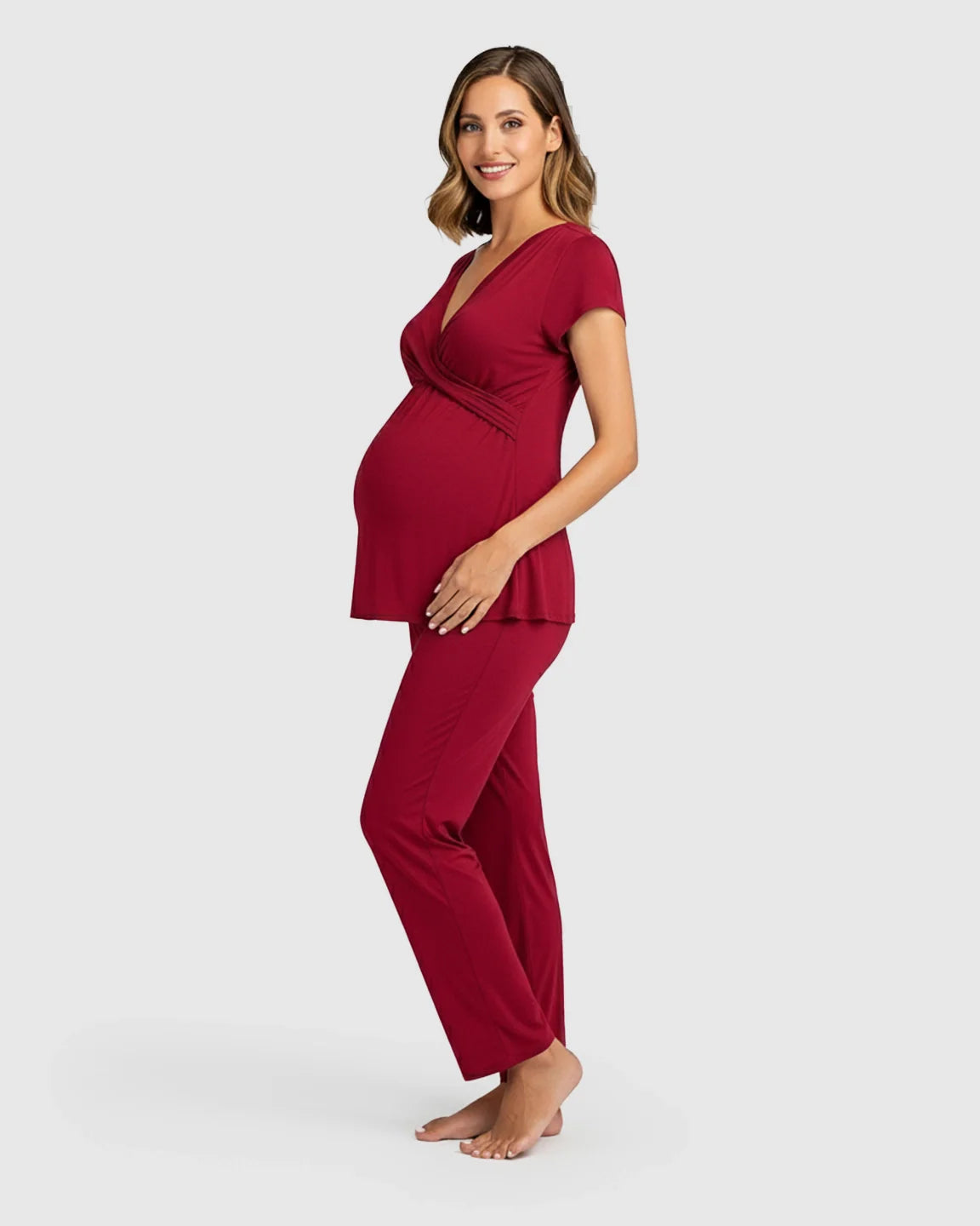 Smiling pregnant woman in a red short-sleeve wrap V-neck maternity and nursing sleepwear set.
